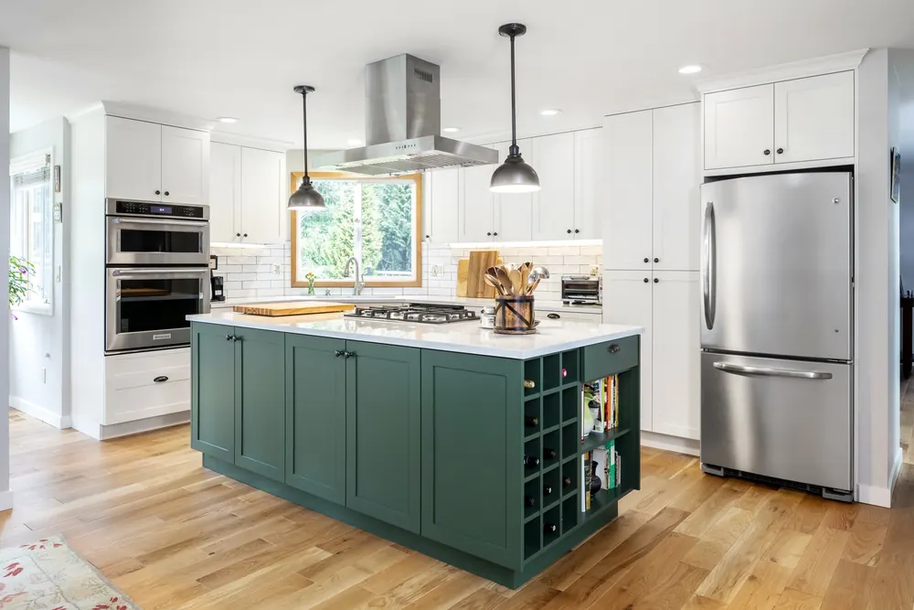 White kitchen with a green island, open shelving and wine cubbies